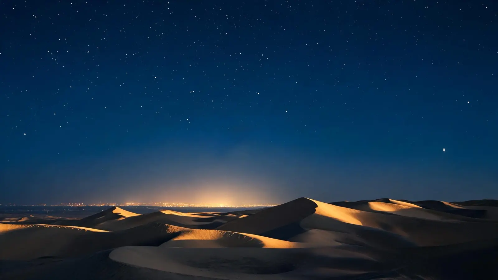 Wüstendünen bei Nacht, am Horizont das Licht einer Stadt (KI-Illustration)